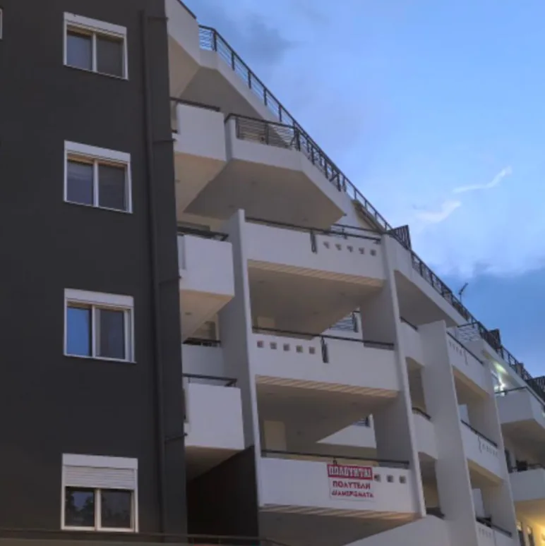 Η πρόσοψη της πολυκατοικίας στη Συρράκου 5 και Αιγείρας 3, με λευκά μπαλκόνια και γκρι όψη